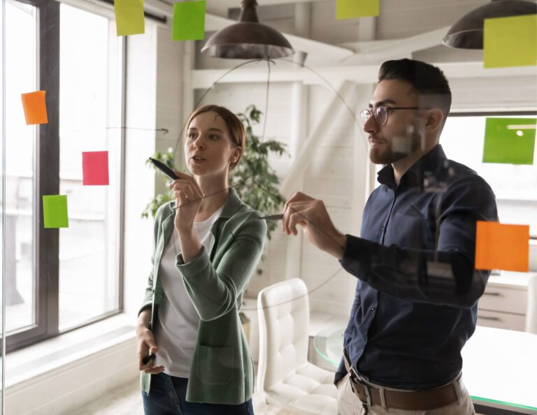 A man and a woman working through workflow examples on sticky notes