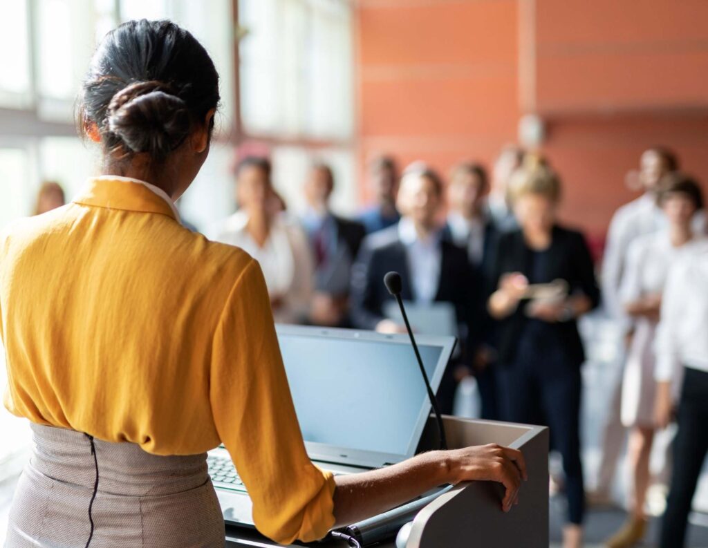 Public speaker addresses room of business associates.