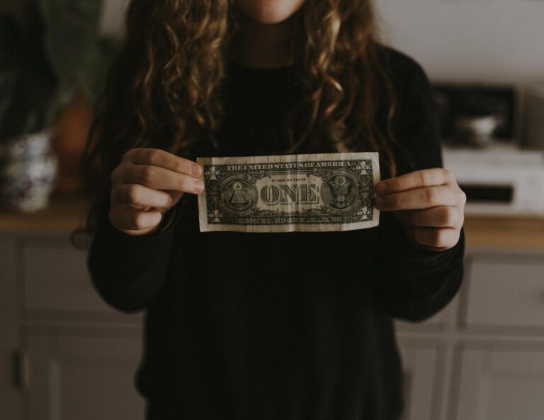 Girl holds dollar bill.