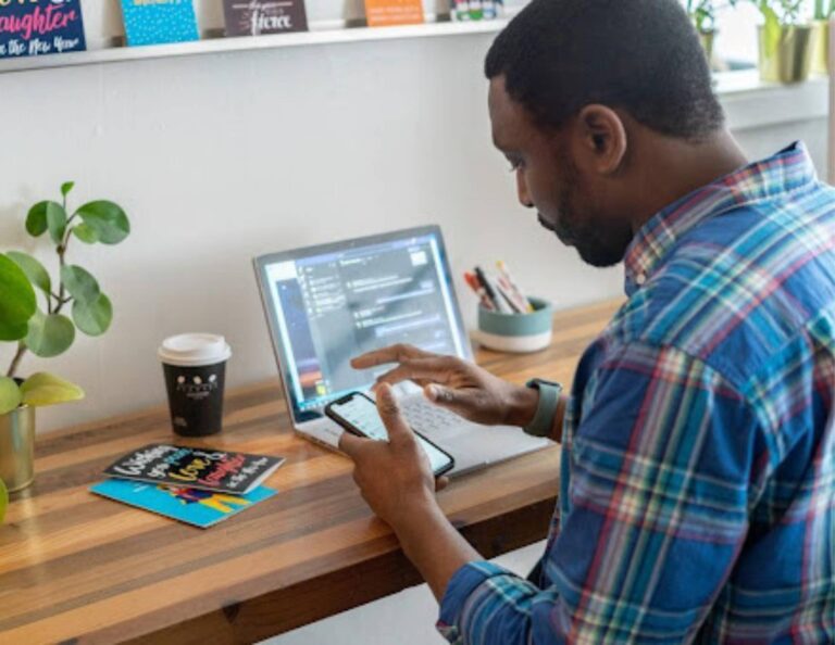 Man working on a pricing guide on his phone and laptop
