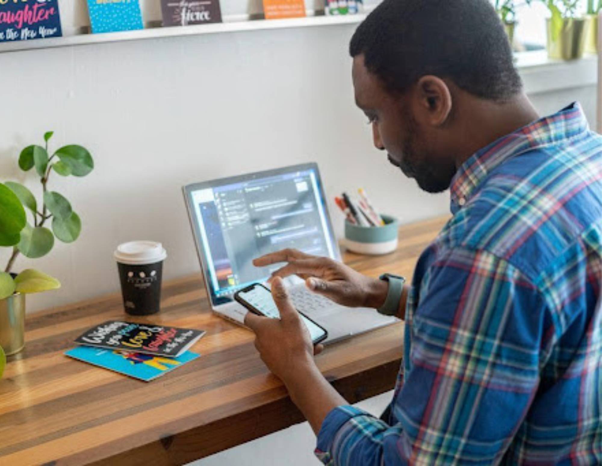 Man working on a pricing guide on his phone and laptop