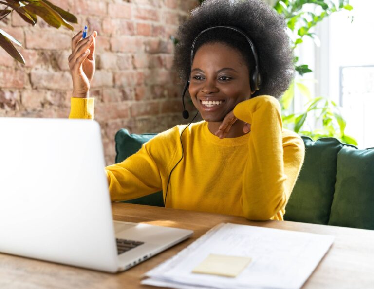 Woman at her computer with a headset on working on her sales strategy