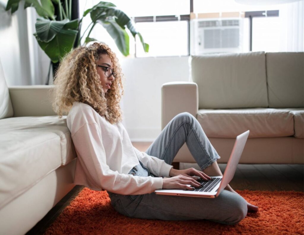 a woman sitting on the floor on her laptop