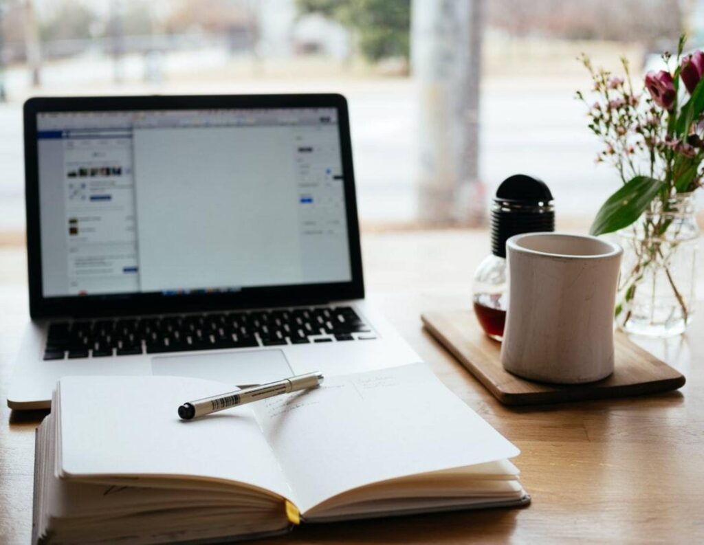 Journal on a desk with laptop open in the background