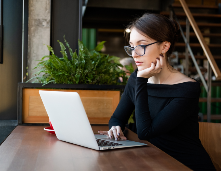 Woman thinking at her computer as she writes an email.