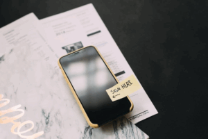 an iphone with a post-it note saying 'sign here'