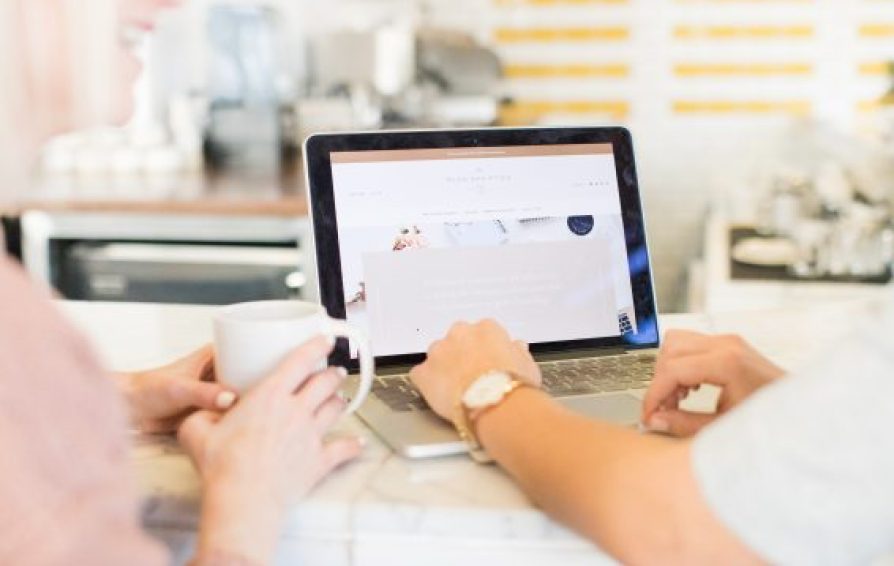 Close up of two people looking at a website on their laptop.