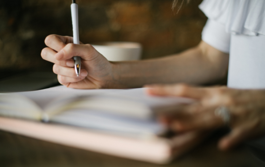 a woman holding a pen writing in a book