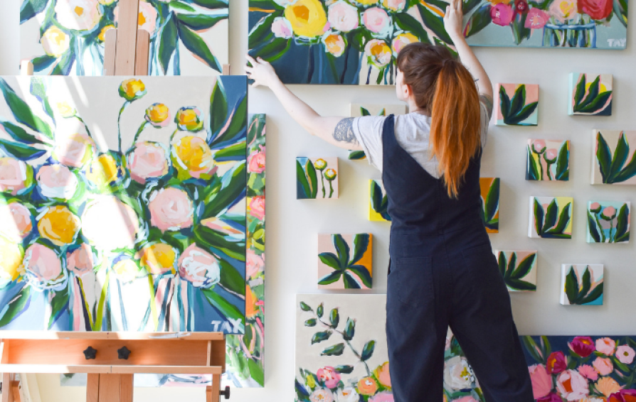 an artist hanging paintings on a wall