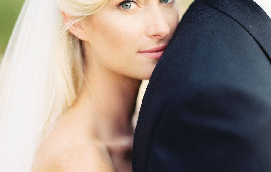 Close up of a bride looking at the camera as she leans on the groom.