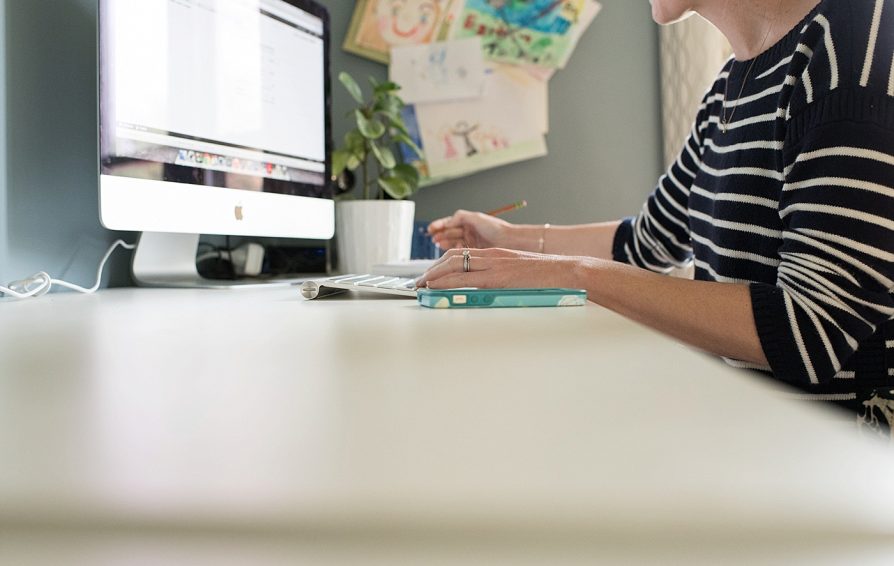 A woman works at a desk on an iMac.