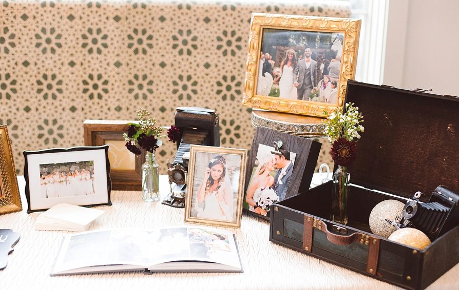 A table decorated with wedding photographs, old cameras, and a vintage suitcase.