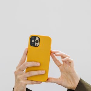 A woman's hand snapping a photo with her phone against a simple white background.