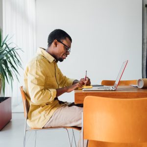 Handsome young man sitting in office at his desk and working at laptop