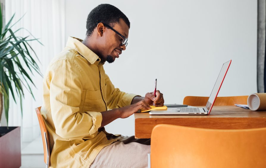 Handsome young man sitting in office at his desk and working at laptop