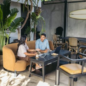 5807419 Colleagues sitting in a couch of a modern coffee shop, drinking coffee and working with laptop