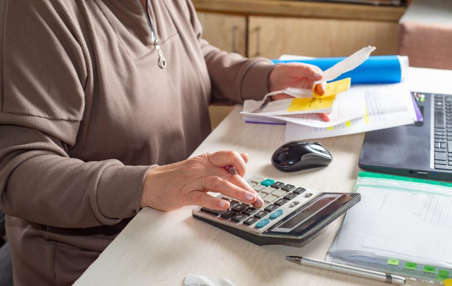 Accountant counts on a calculator and looks at receipts at his desk in the office