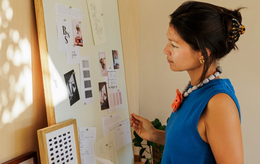 Side view of creative woman organizing ideas on a moodboard standing in her cozy home studio