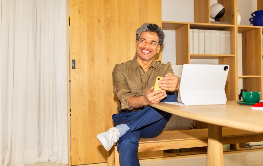 Middle-aged man sitting at home, looking at someone and smiling