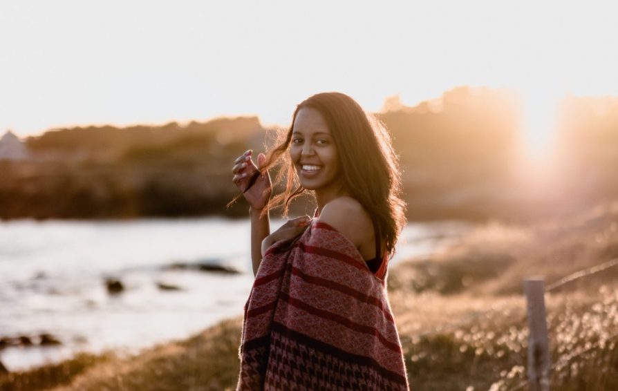 a woman posing for a photo in front of a lake