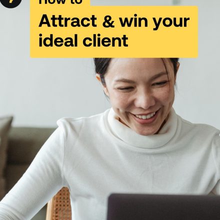 Woman looks at screen and smiles wearing a white turtleneck on the cover of the attract and win your ideal client guide.
