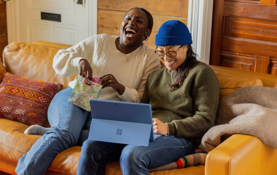Two marketers laugh at something on a computer.