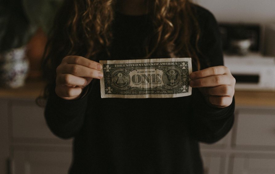 Girl holds dollar bill.