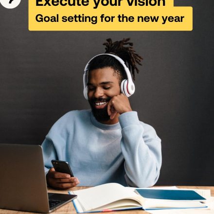 Man laughs wearing headphones on the cover of the Executing Your Goals Guide.
