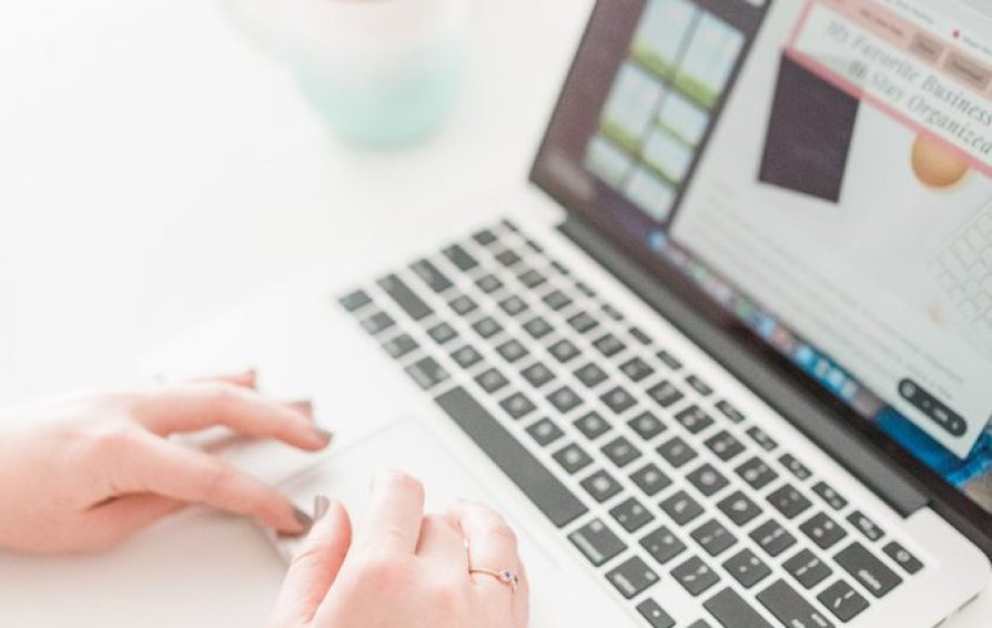 Close up of a woman's hands typing on a laptop.