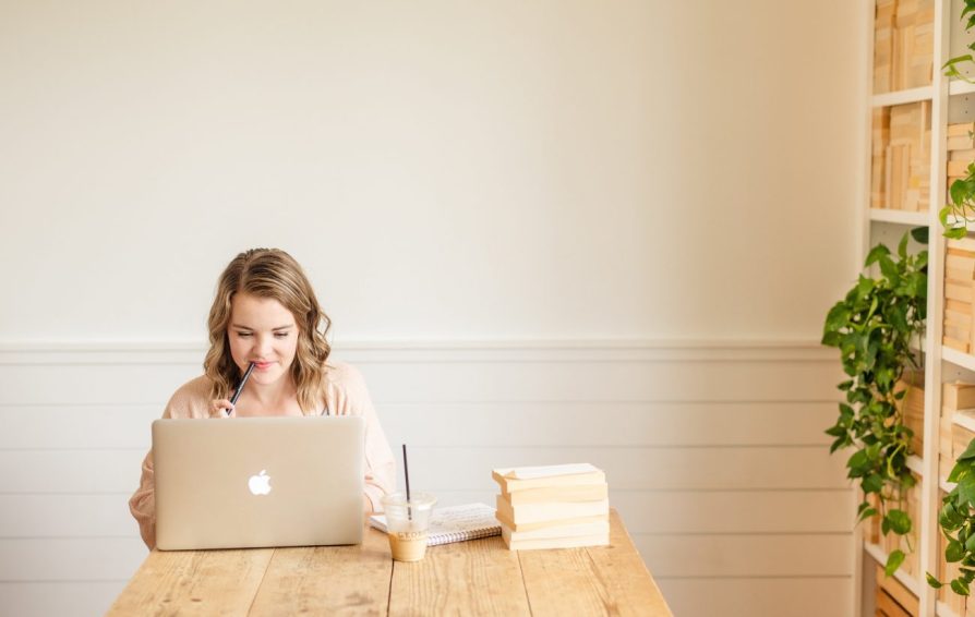 woman on a laptop with a stack of papers