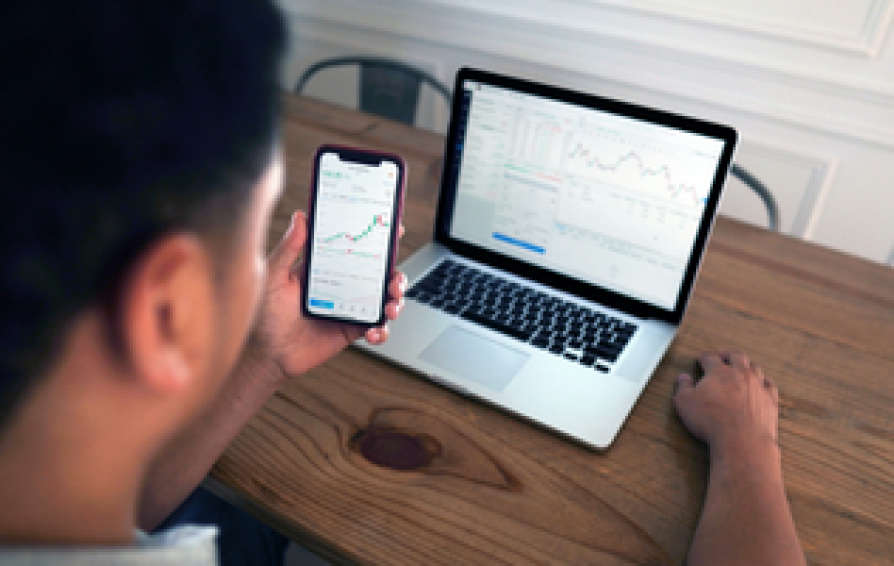 person looking at finance dashboards on their phone and computer