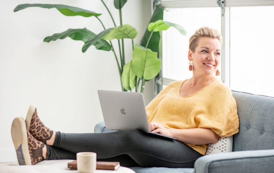 Woman with feet up using a laptop and smiling.