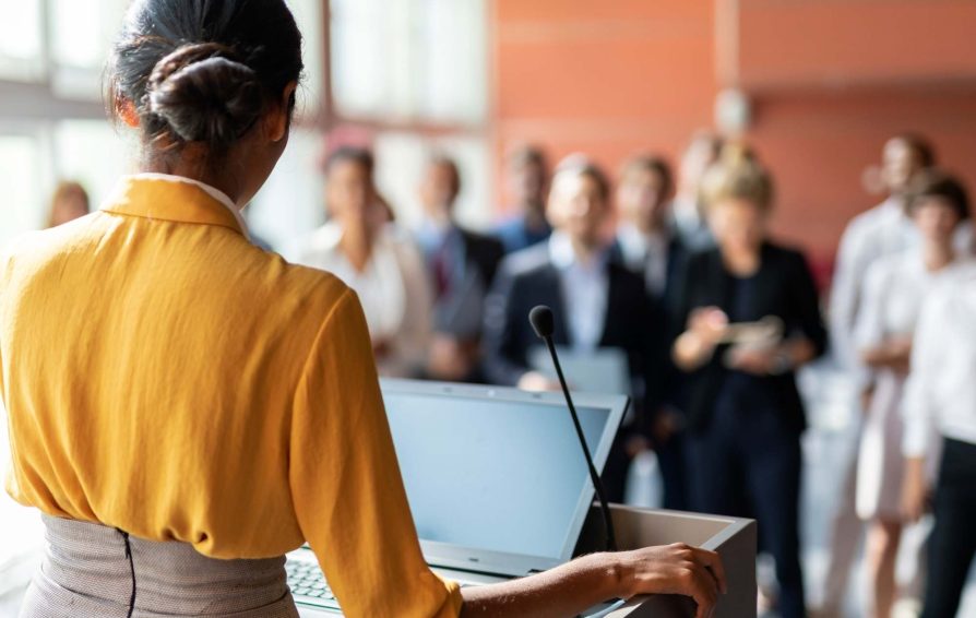 Public speaker addresses room of business associates.