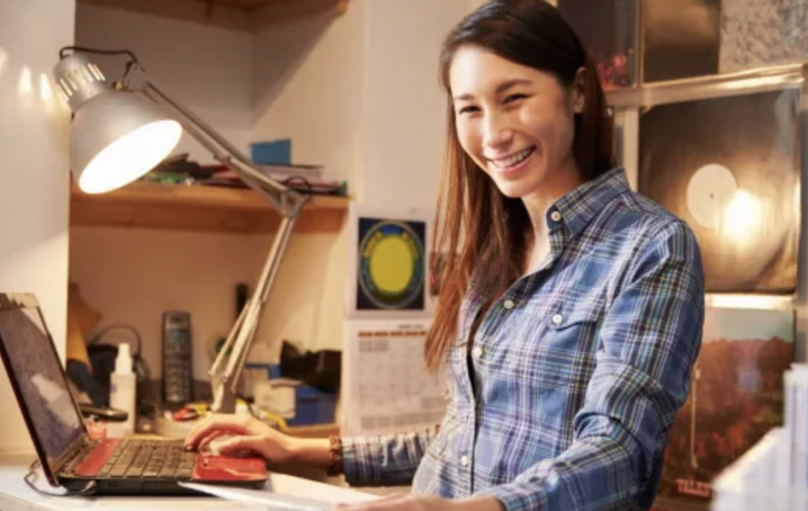 a woman at a desk smiling and learning how to control her business expenses
