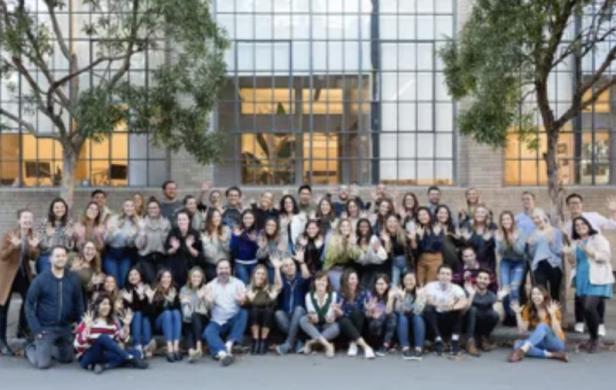 a group of people smiling and posing in front of a modern building