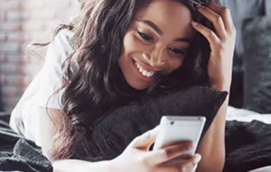 a smiling woman on a bed looking at her smartphone with the Snap, Inc. logo in the corner