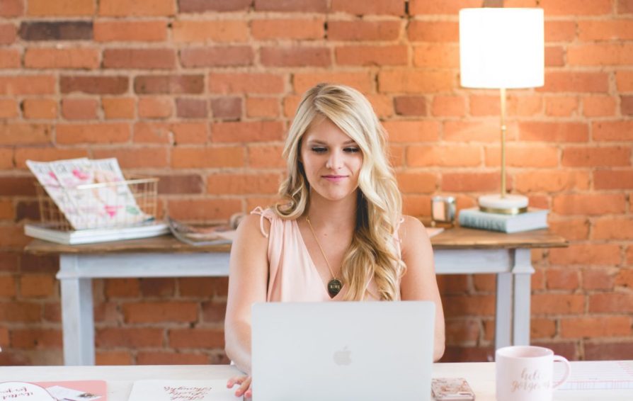 Woman with blonde hair works at laptop.