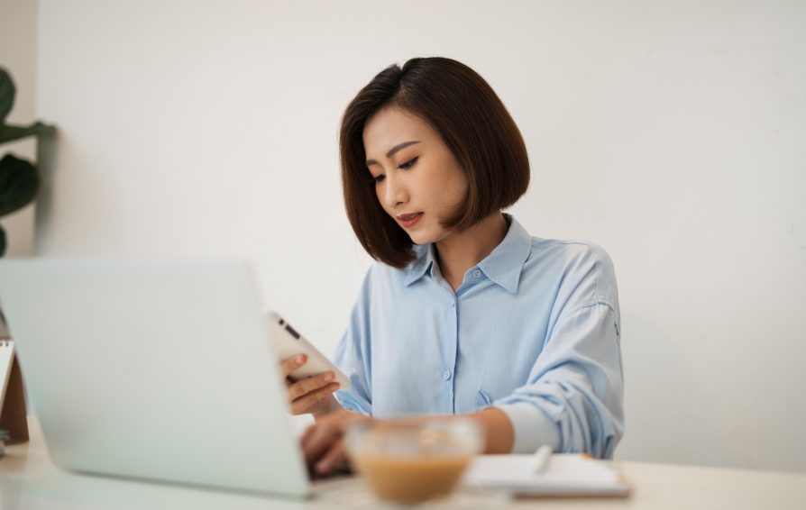 a woman with a laptop and phone learning how to discover her leadership style