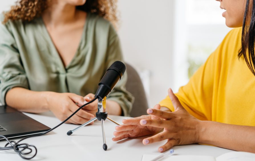 two women sitting by a microphone discussing how to create an inclusive space within their business