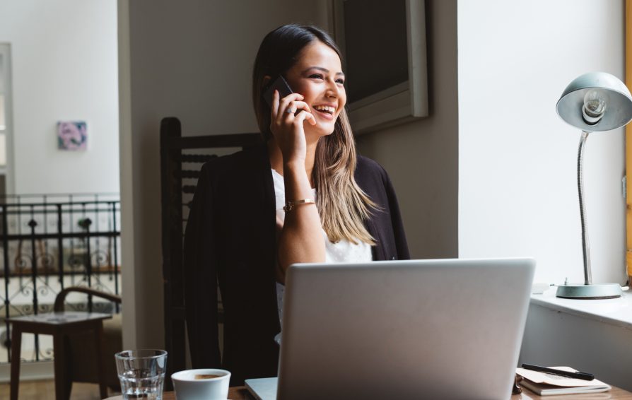 Businesswoman Talks On A Phone While Working On Laptop