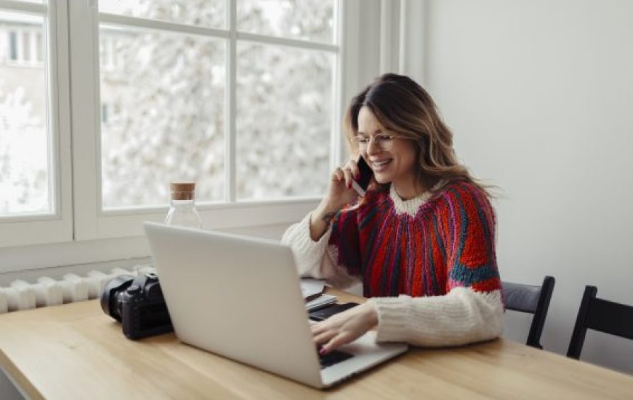 woman on the phone using a laptop learning about the Employee Retention Tax Credit
