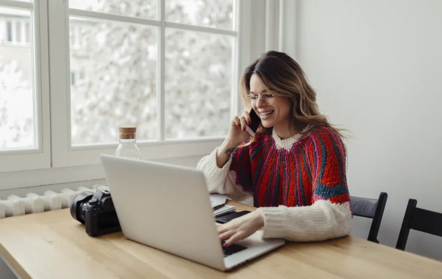 Woman working on laptop answers a phone call.