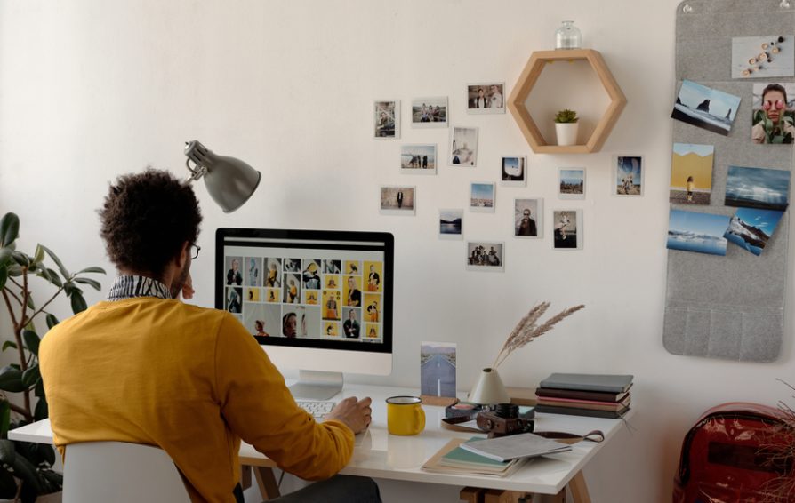 Horizontal shot of young man wearing eyeglasses sitting at desk surfing the Internet