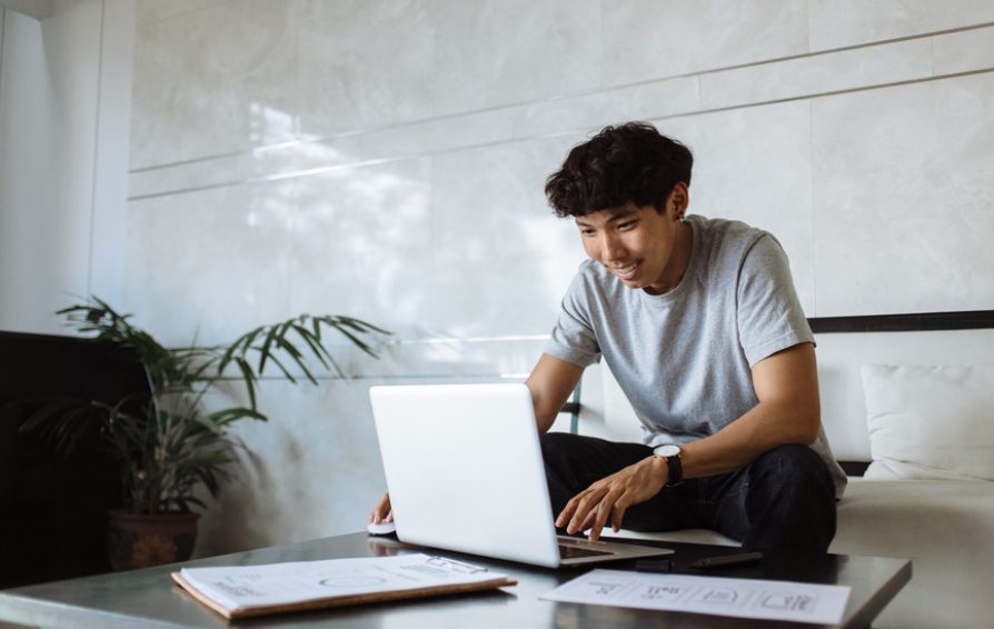 Young Designer Working At Laptop And Sketches