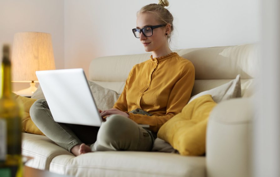 Woman working on computer while lounging on couch.