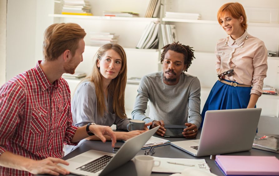 Young coworkers discuss around a table.