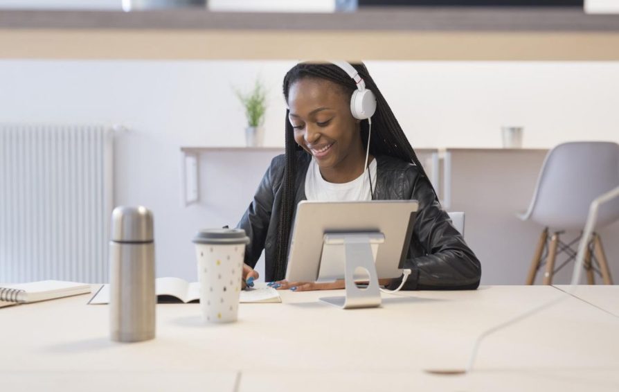 a woman on a laptop with headphones learning how to pitch podcasts