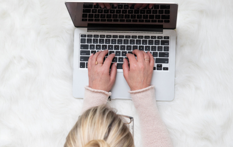 blonde woman typing on a computer at a desk