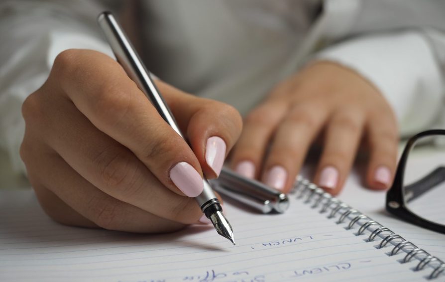 a woman holding a pen writing in a notebook