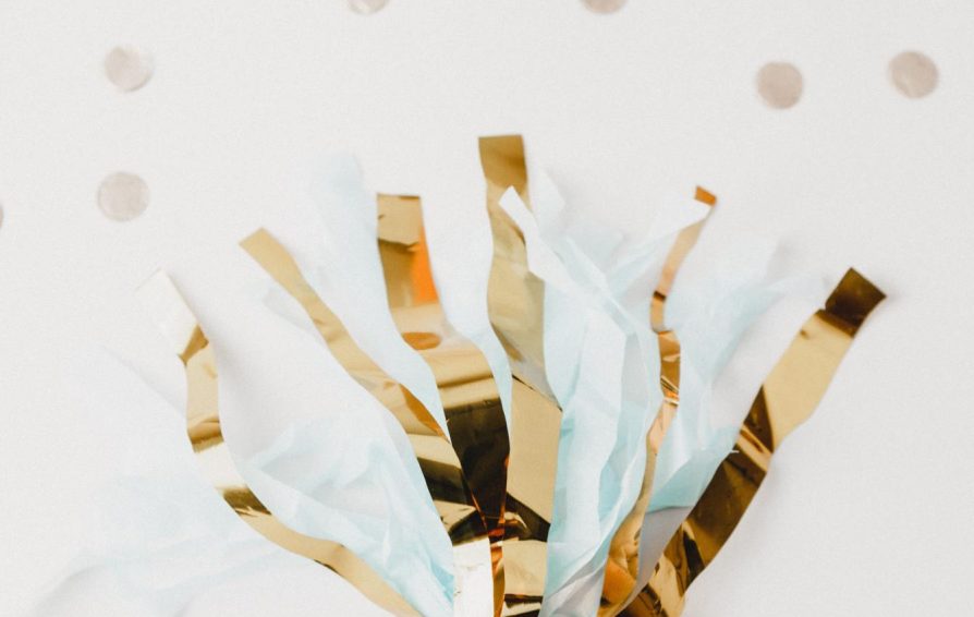 A gold and teal party streamer on a polka dotted background